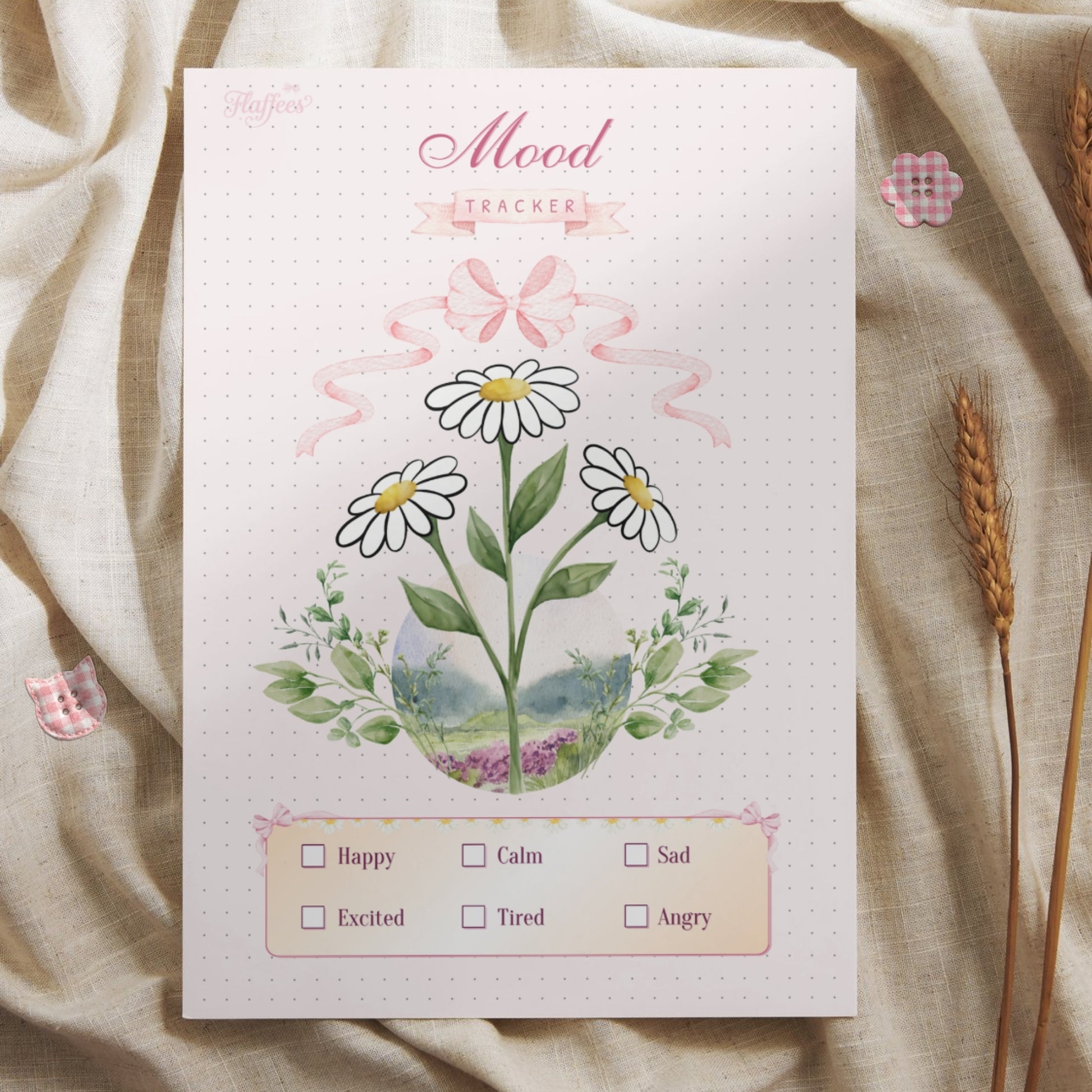 Lifestyle mockup of the daisy mood tracker printed on high-quality paper for a bullet journal, placed on a textured fabric background. The scene is decorated with rustic wheat stalks and small pink checkered buttons, emphasizing the cozy and aesthetic nature of the floral journaling page.