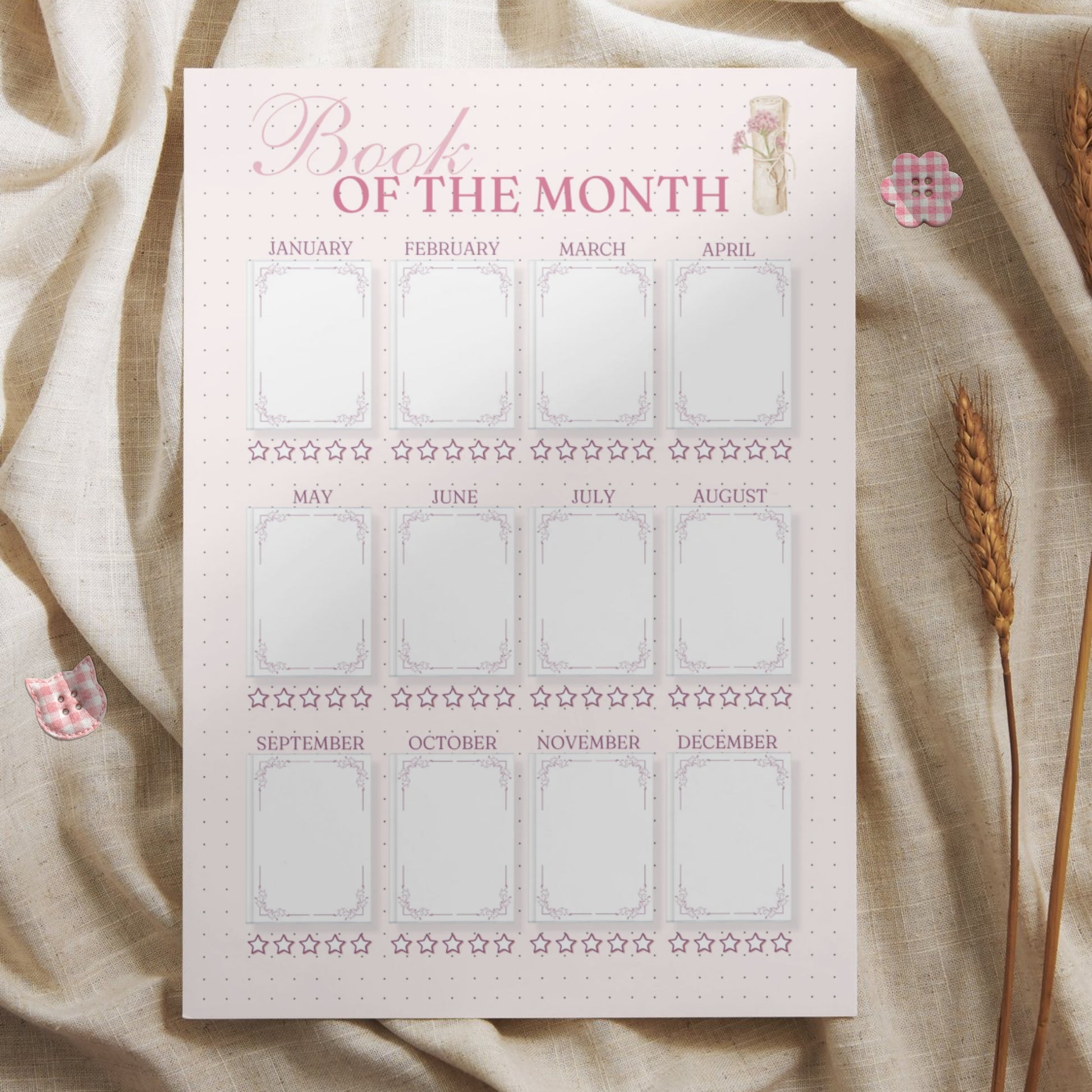 Lifestyle mockup of the yearly book tracker printed on high-quality paper, styled with rustic wheat stalks and pink checkered buttons on a neutral fabric. Highlights the cozy and elegant feel of the printable bullet journal page, perfect for book lovers and stationery enthusiasts.