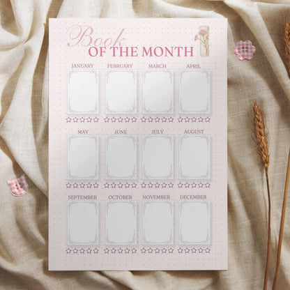 Lifestyle mockup of the yearly book tracker printed on high-quality paper, styled with rustic wheat stalks and pink checkered buttons on a neutral fabric. Highlights the cozy and elegant feel of the printable bullet journal page, perfect for book lovers and stationery enthusiasts.