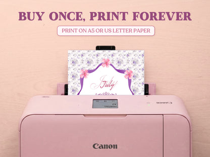 A printable July cover page featuring a purple floral pattern being printed from a pastel pink Canon printer on a wooden desk setup. Includes large decorative text reading 'BUY ONCE, PRINT FOREVER' and 'PRINT ON A5 OR US LETTER PAPER' to highlight its printable features for a bullet journal.