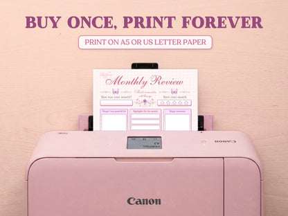 A printable monthly review page being printed from a pastel pink Canon printer on a light wood desk setup. The image template includes large decorative text saying 'BUY ONCE, PRINT FOREVER' and 'PRINT ON A5 OR US LETTER PAPER' to highlight its printable features for a bullet journal.