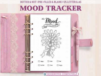 A bullet journal mood tracker page featuring a beautiful tulip bouquet line-art design, displayed inside an open pink leather binder decorated with lace. Includes a mood key at the bottom. Labeled as GoodNotes compatible.